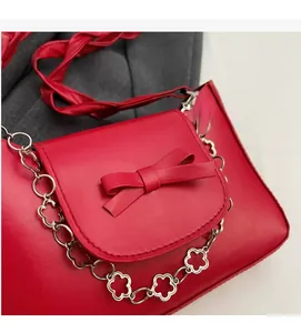 Detail of red leather shoulder bag with decorative bow and silver floral metal chain