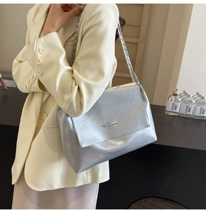 Détail d'un sac à bandoulière argenté métallisé avec finition brillante et chaîne
