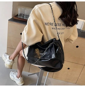 Détail du sac cabas en cuir noir brillant avec chaîne argentée et rabat métallique