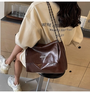 Détail du sac bandoulière en cuir ciré marron foncé avec barre argentée et bandoulière chaîne