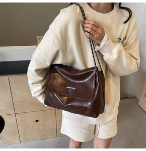 Détail du sac bandoulière marron foncé à chaîne avec texture cuir sur sweat blanc