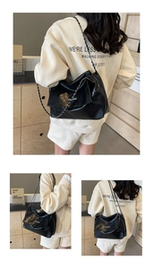 Détail du sac cabas en cuir noir brillant avec bandoulière chaîne et fermoir métal