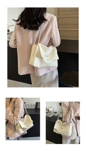Détail du sac à bandoulière crème en cuir brillant avec bandoulière chaîne et barre argentée