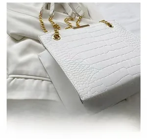 Detail view of white crocodile pattern tote bag with gold chain strap and metal trim
