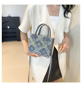 Detail of denim crossbody bag featuring frayed edges, grid texture and green stars