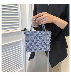 Close-up of blue denim checkerboard tote bag with distressed fringe and carrying handle