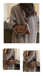 Detail of dark brown leather crossbody bag featuring twist strap and silver floral chain