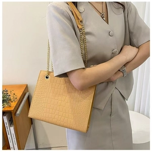 Detailed view of beige crocodile embossed leather and elegant gold chain strap