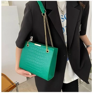 Detail of green crocodile texture shoulder bag with elegant gold metal chain strap