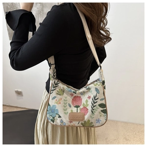 Detail of retro floral embroidery on high-capacity woven shoulder bag with logo