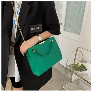 Close-up of green crocodile texture tote bag with gold chain strap and metal handle