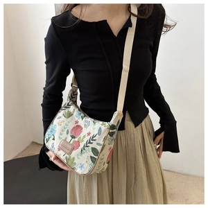 Detail of floral jacquard crossbody bag showing the leather logo and woven shoulder strap