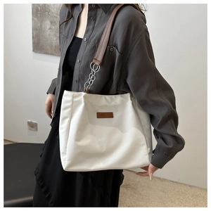 White canvas tote bag with leather strap and metal chain for versatile commuting use