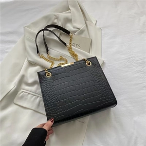 Detail of black faux leather tote with crocodile texture and gold chain strap