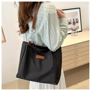 Large black nylon tote bag with leather chain strap for women in a minimalist interior