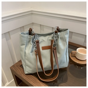 Detail of green tote bag featuring textured fabric, leather straps and silver chain link