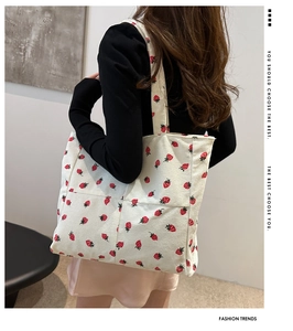 Detail of strawberry corduroy tote bag showing material texture on model's shoulder