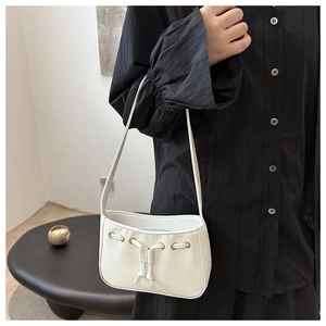 Close-up of white leather underarm bag featuring drawstring detail and gold eyelets