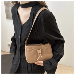 Detail of khaki drawstring underarm bag showing the smooth PU leather texture and metal eyelets