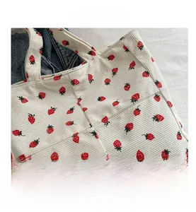 Close-up of cream corduroy tote bag with strawberry pattern and textured vertical stripes