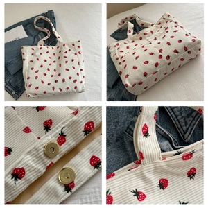 Detail view of strawberry print corduroy tote bag showing magnetic buckle and stitching