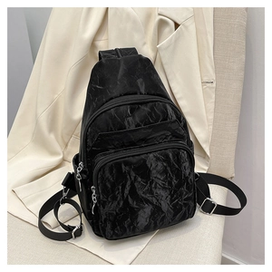 Detailed view of black textured mini chest bag with double zipper pockets and adjustable strap