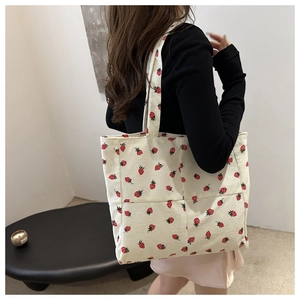 Détail du sac fourre-tout en velours blanc avec motif imprimé de fraises rouges