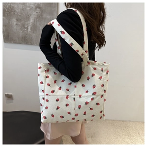 Sac tote en velours côtelé blanc avec imprimé fraise porté par un mannequin en mode casual