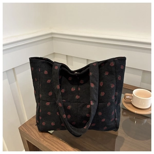 Détail du cabas en velours côtelé noir à motifs fraises rouges et texture côtelée douce