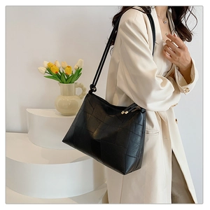 Large capacity black tote bag with geometric stitching shown on shoulder by model