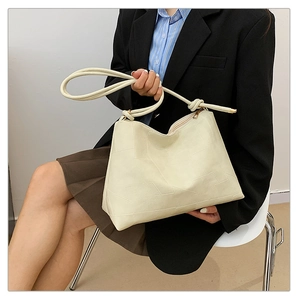 Detail of off-white tote bag showing geometric stitching and knotted rope straps