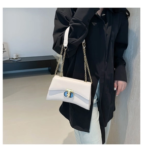 Détail du sac carré en cuir blanc cassé avec élégant fermoir ovale bleu et doré