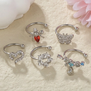 Detail shot of five silver 18K plated ear cuffs with various rhinestone charms on a textured base