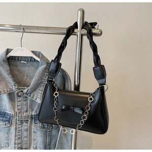 Close-up of black PU handbag with metal flower chain and woven shoulder strap
