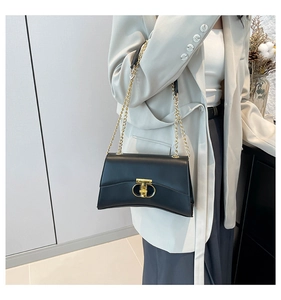 Détail d'un sac bandoulière en cuir noir avec fermoir doré chic et bandoulière en chaîne