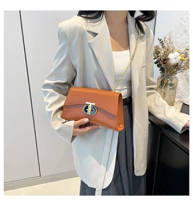 Détail du sac bandoulière en cuir marron avec chaîne dorée et fermoir en métal en forme de T