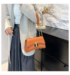 Détail d'un sac à bandoulière marron avec fermoir ovale doré et texture en cuir mat
