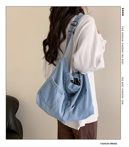 Detail of light blue washed denim tote bag with front pocket and adjustable strap