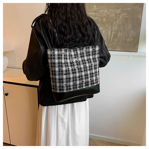 Detail of checkered tote bag featuring mini bow patterns and silver bow pendant charm