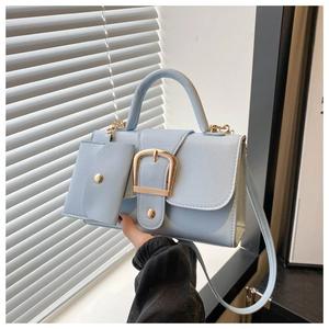 Sky blue leather handbag with gold buckle and matching mini pouch in natural light
