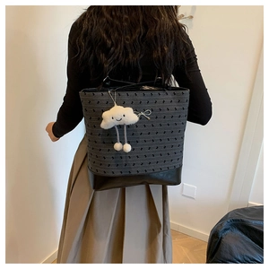 Detail view of large grey polka dot tote bag with cute cloud charm on model back