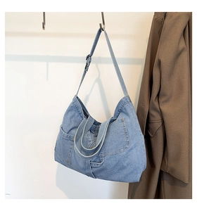 Close-up of light blue denim tote bag with adjustable strap and visible side pocket