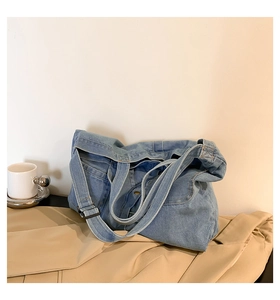 Detail view of the light blue denim tote bag showing reinforced stitching and metal buckle