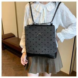 Detailansicht eines grauen Polka-Dot-Rucksacks mit eleganter Metallschleife