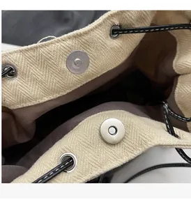Detail of herringbone canvas bag showing metal magnetic closure and black drawstring