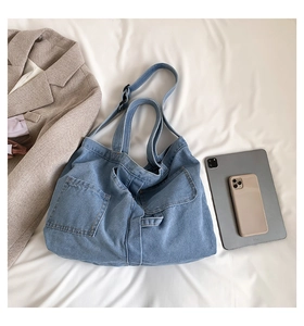 Flat lay of light blue washed denim tote bag with tablet and blazer for commute