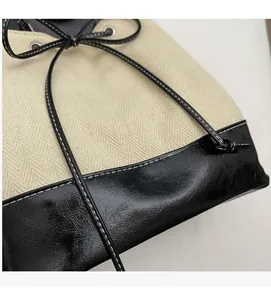 Detail of drawstring bucket bag with beige herringbone fabric and black faux leather