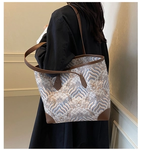 Detail of the large tote bag showing printed wave patterns and brown leather handles