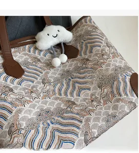 Detailed macro view of wave-pattern jacquard tote fabric with plush cloud pendant