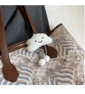 Detail of tote bag with wave patterns, leather straps, and a cute cloud plush charm